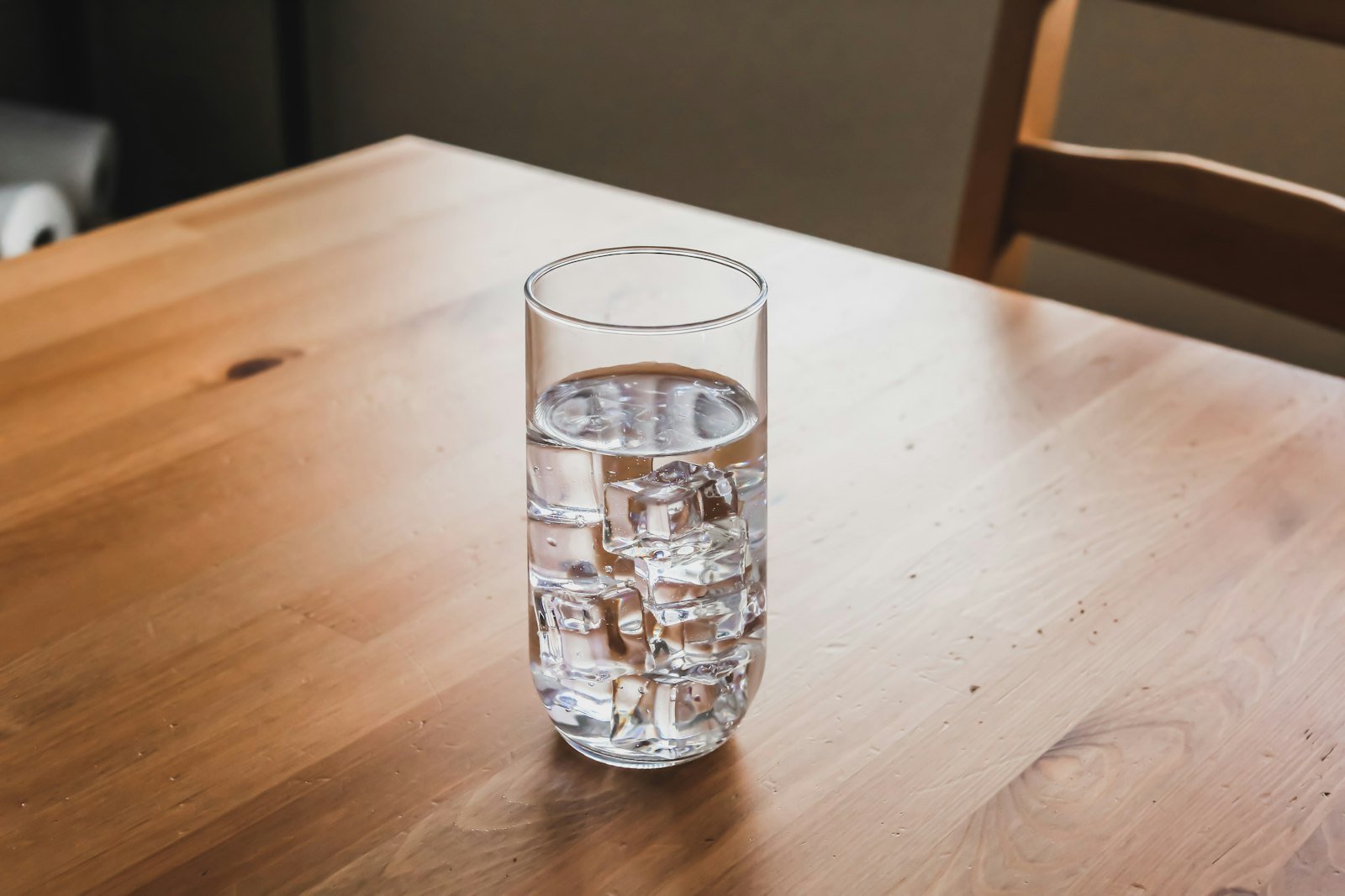 Verre d'eau posé sur une table en bois, en lumière naturelle
