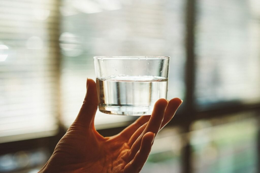 Main qui tient un verre d'eau à moitié rempli